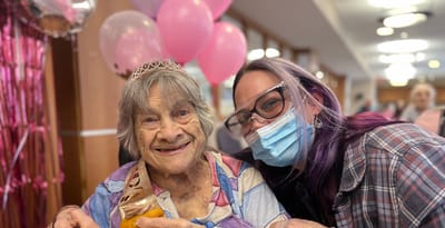 Residents celebrating with balloons and a caregiver.