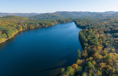 Aerial view of a serene lake surrounded by autumn foliage.