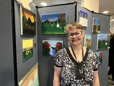 Resident posing next to displayed artwork