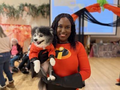 Costumed staff member holding a dog at a celebration.