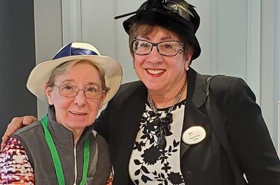 Two women wearing hats and smiling together