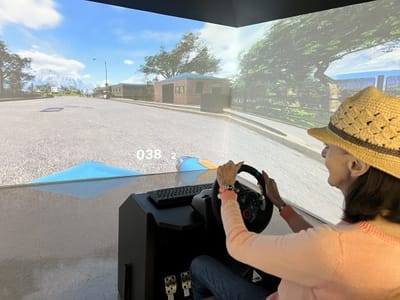 Resident using a driving simulator in an activity room.