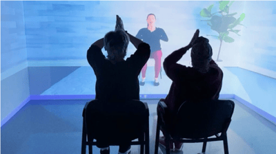 Residents engaging in seated exercise with a virtual instructor.