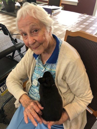 Resident holding a black rabbit, smiling.