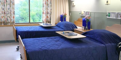 Two hospital beds in a patient room with floral decor