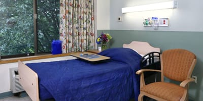 Patient room with a bed and chair.