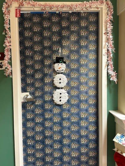 Festively decorated door with a snowman motif.