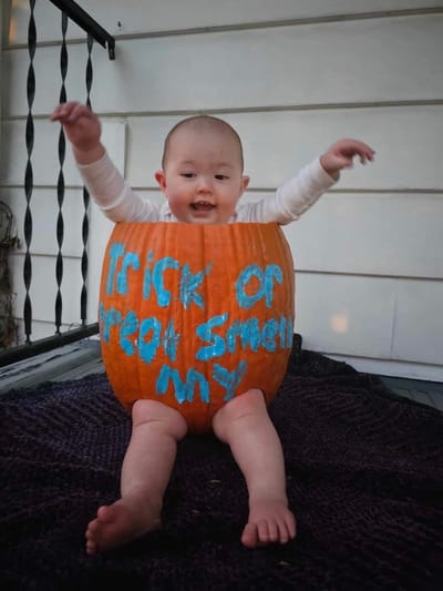 Baby sitting inside a painted pumpkin.
