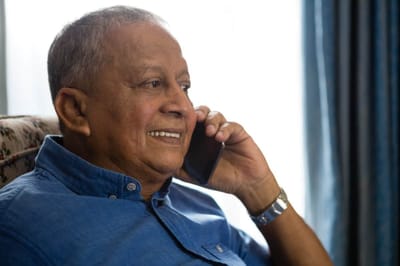Senior man smiling on the phone in a cozy setting.