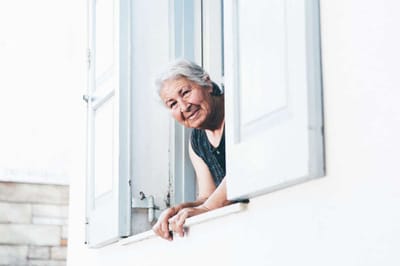 Elderly woman smiling from an open window