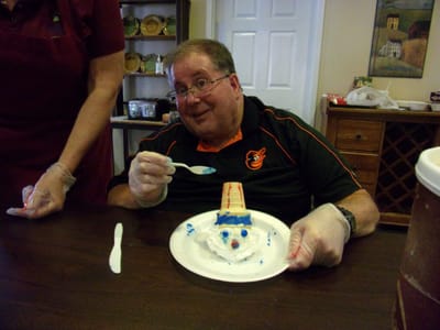 Resident smiling while decorating a cake.