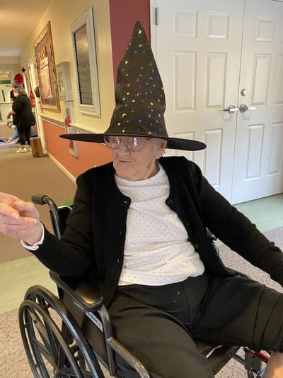 Resident in wheelchair wearing a festive hat.