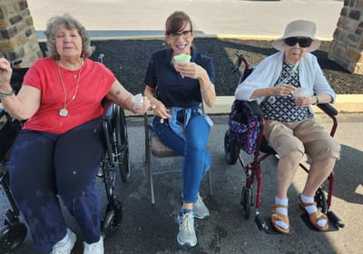 Residents enjoying ice cream outdoors with staff.