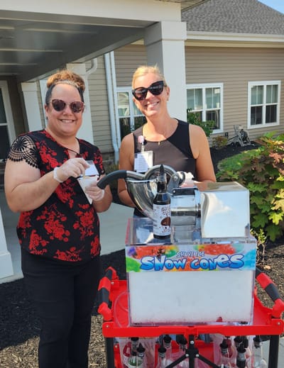 Staff and resident enjoying snow cones outdoors.