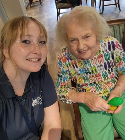 A staff member smiles with a resident during an activity.
