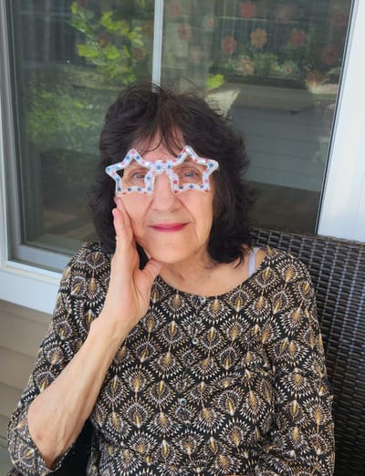 Senior woman wearing fun star-shaped glasses outdoors.
