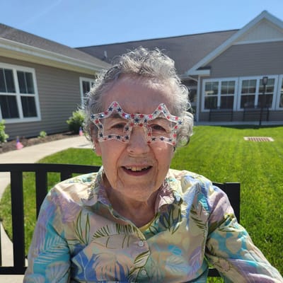 Smiling resident wearing star-shaped glasses outside