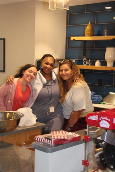 Three staff members smiling in a kitchen area.