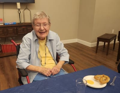 Elderly woman smiling at a table with food