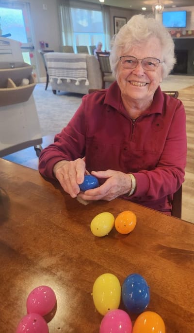 Senior woman enjoying an activity with colorful plastic eggs.