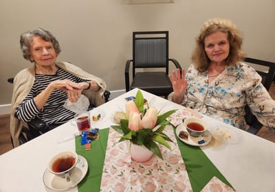 Two residents enjoying tea and dessert together.