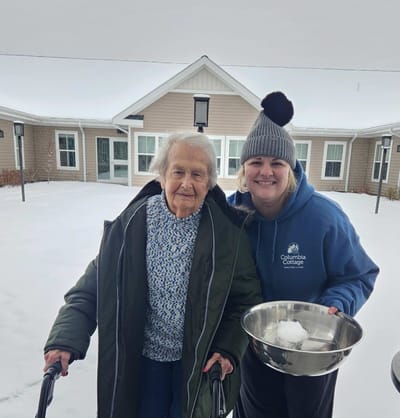 Resident and staff member enjoying outdoor snow activity.