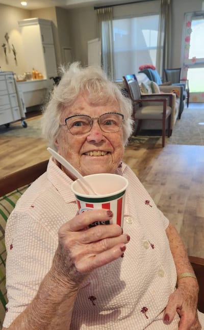 Elderly woman enjoying a treat in a common area.