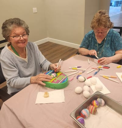 Two senior women painting decorative eggs