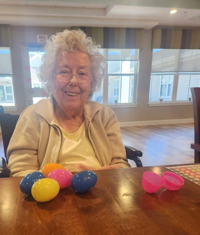 Senior resident enjoying Easter activities with colored eggs.