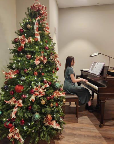 Resident playing piano near decorated Christmas tree