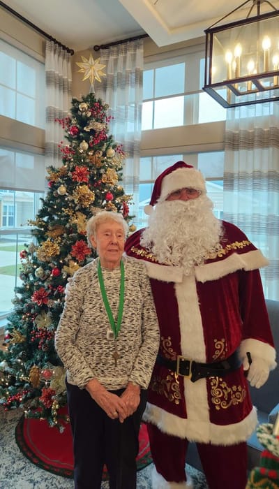 Resident and Santa Claus by a decorated Christmas tree