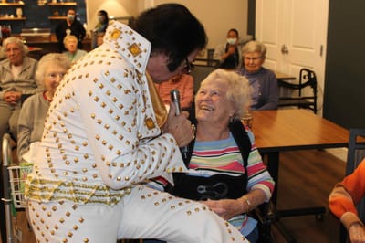 Elvis performer engaging with resident during an event.
