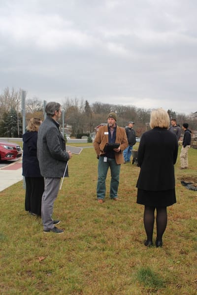 Group of people discussing outdoors in a grassy area.