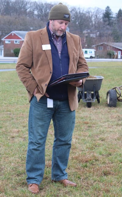 A man outdoors reviewing a document.