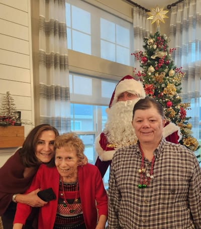 Residents and staff celebrate with Santa in festive attire.