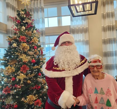 Resident with Santa Claus by a decorated Christmas tree