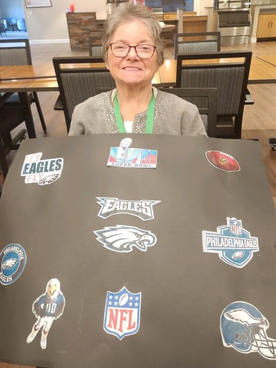 Resident enjoying a craft activity with sports decorations.