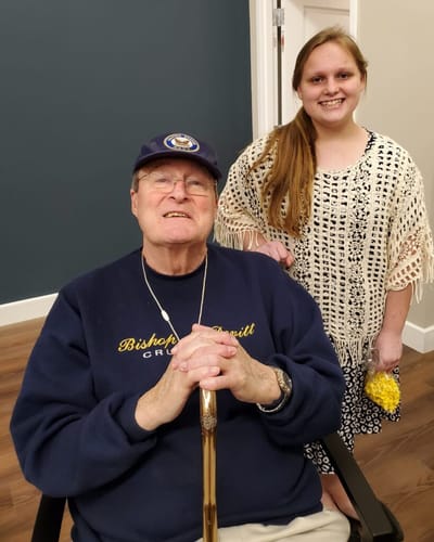 Senior man and young woman smiling together indoors.