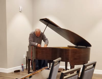 Elderly man playing the piano in a common area