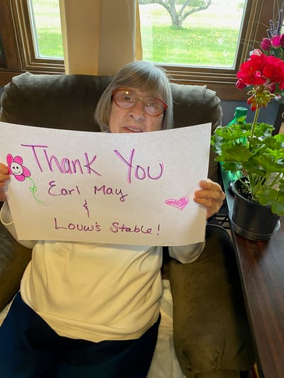 Resident holding a thank you sign with flowers.