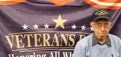Senior veteran posing in front of a banner.