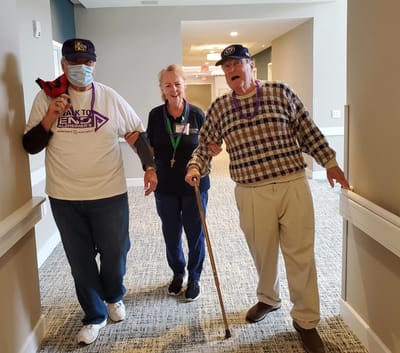 Residents enjoying a walk in the facility hallway.