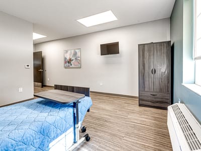 A spacious resident room with a bed and TV.