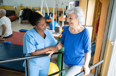 Staff assisting a resident in a therapy area.