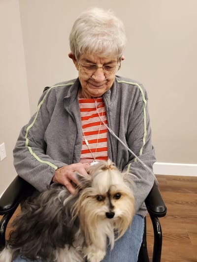 Elderly woman sitting with a small dog.