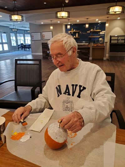 Senior man carving a pumpkin in a common area