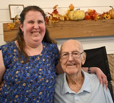 Resident and staff member smiling indoors.