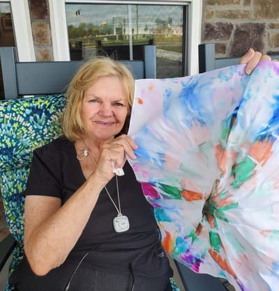 Resident showcasing a colorful art project outdoors.