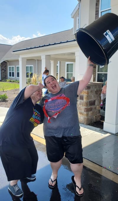 Residents celebrating outdoors with a water bucket