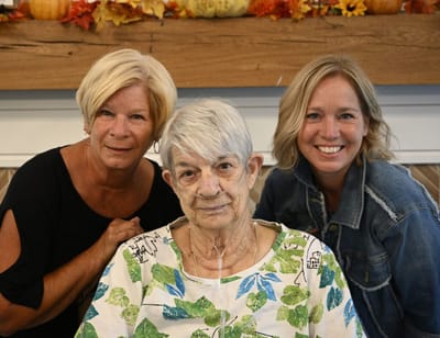 Three women smiling together in a cozy setting.